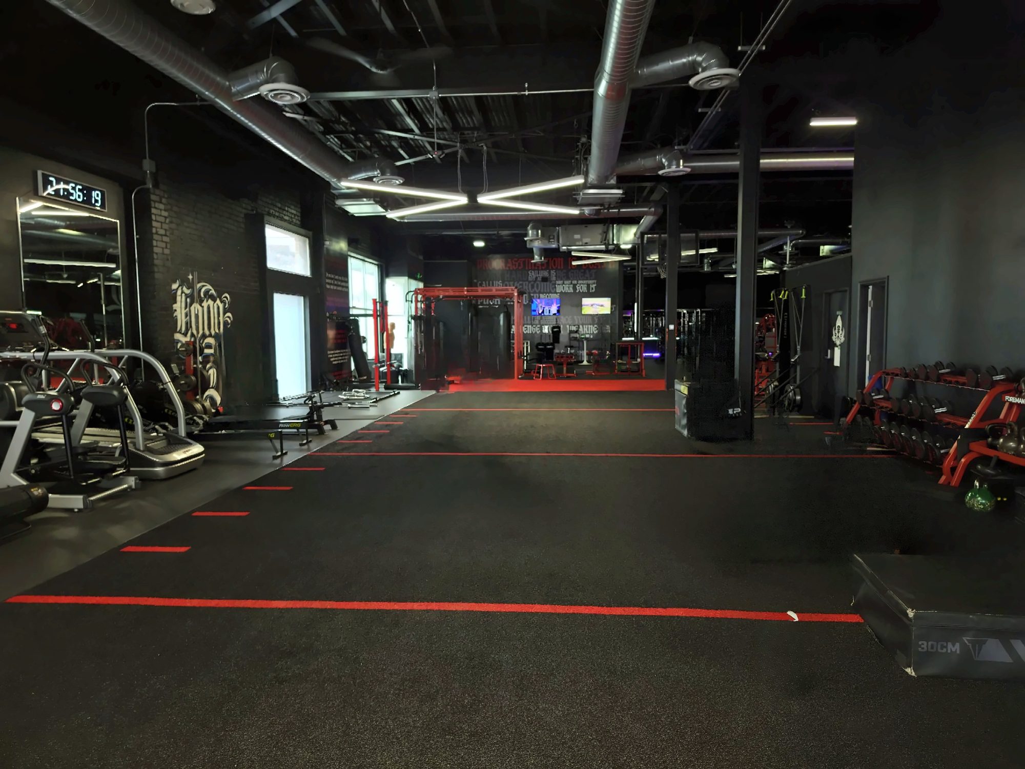 Turf lanes marked in red, dumbbell racks on one side and cardio on the other
