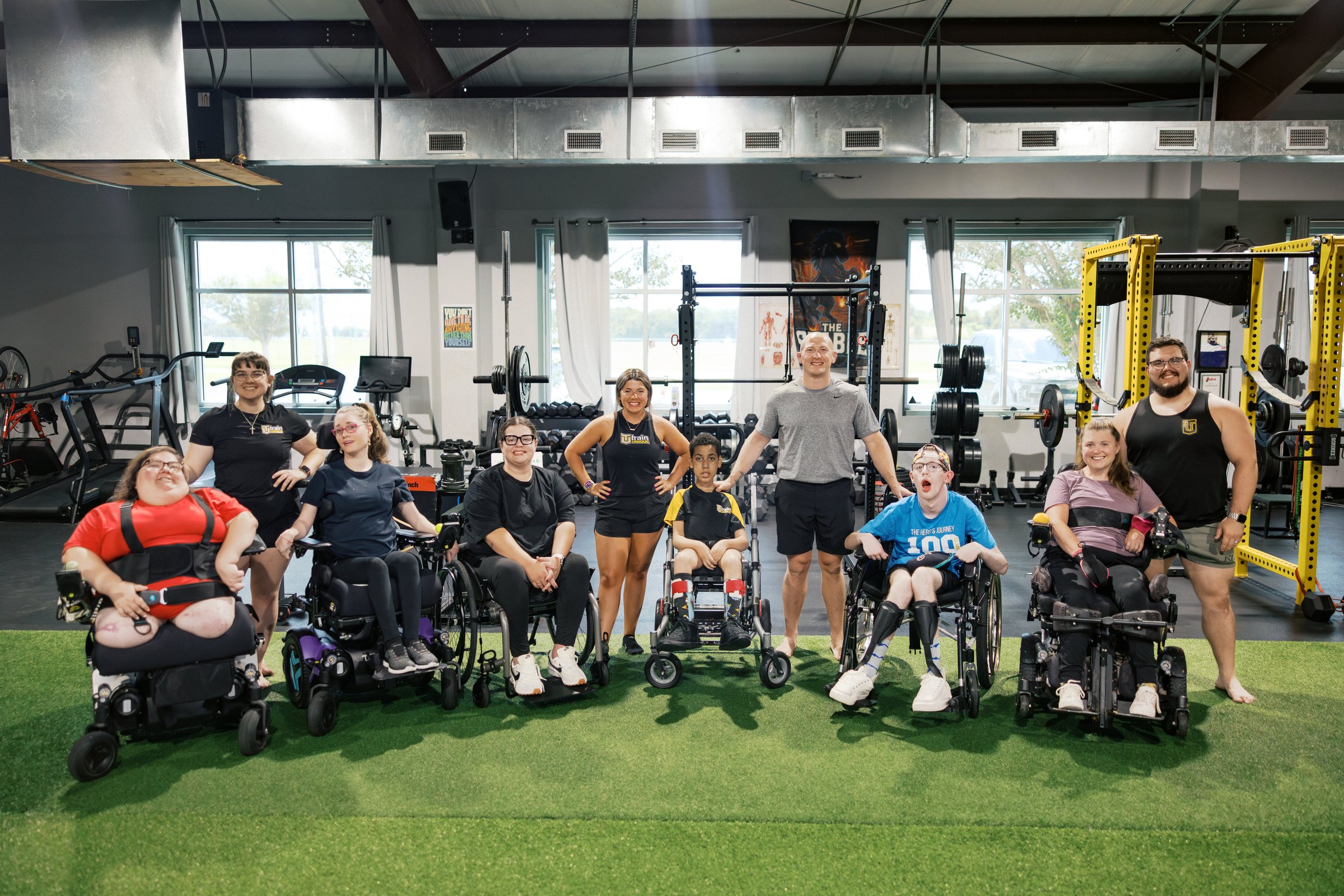A group of athletes, several using wheelchairs, with their coaches on the gym turf